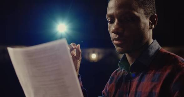 Student rehearsing with a script on stage