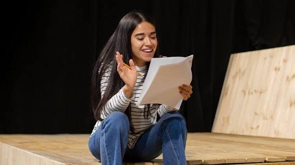 Performer studying a script under stage light